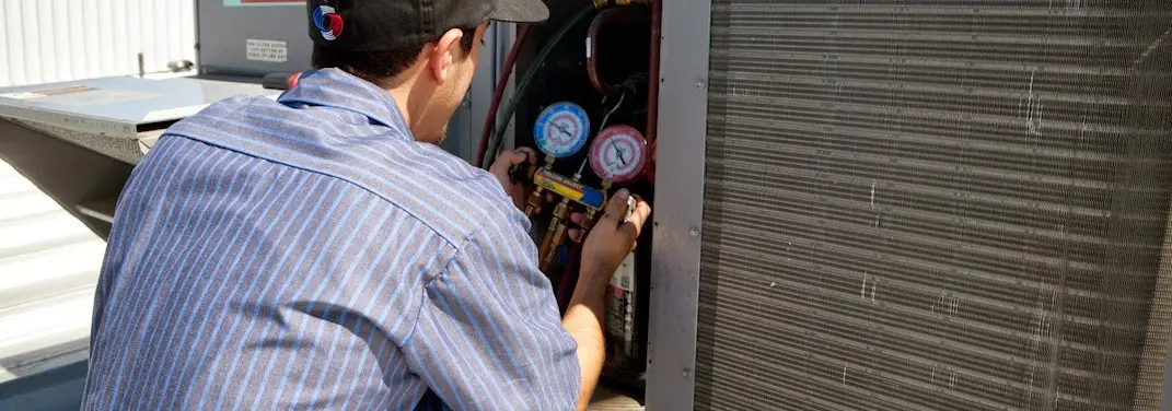HVAC technician servicing a condenser unit in Grand Ledge